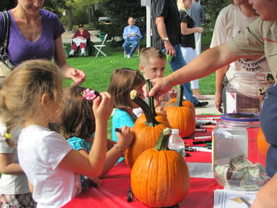 Children decorating pumpkins at an outdoor event