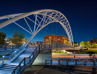 Modern bridge at night with city buildings in background