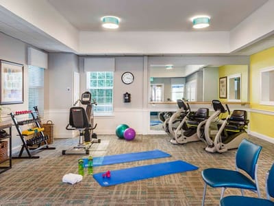 A fitness room with exercise equipment and mats