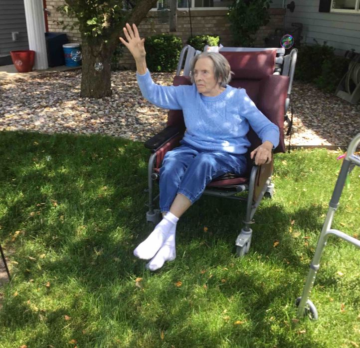 Resident waving while sitting outside on a sunny day