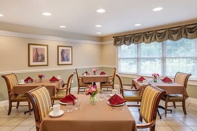 A dining room setup with tables and flowers