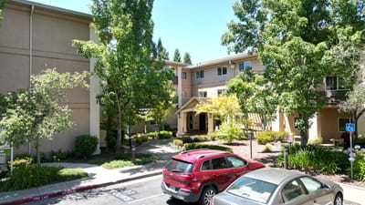 Exterior view of Atria Carmichael Oaks with greenery