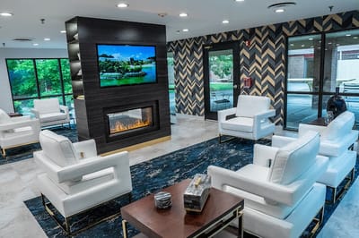 Bright common area with white chairs and fireplace