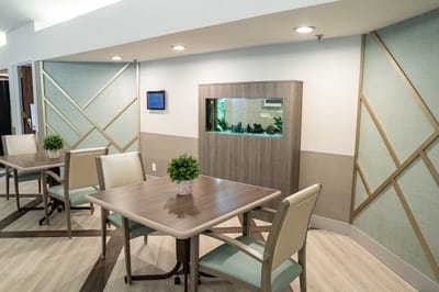 Bright common area with tables and an aquarium