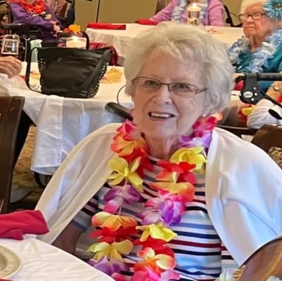 Resident enjoying a festive event with a floral lei