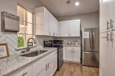 Bright kitchen area with white cabinets and modern appliances