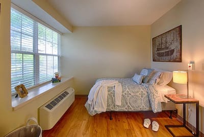 A well-lit private resident room with a bed and decor