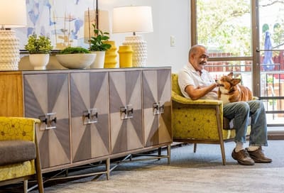 A resident enjoying time with a dog in a common area