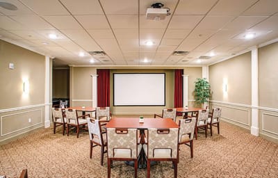 Well-furnished activity room with seating and a presentation screen