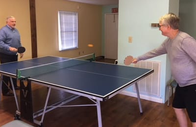 Two residents playing table tennis in a recreational room
