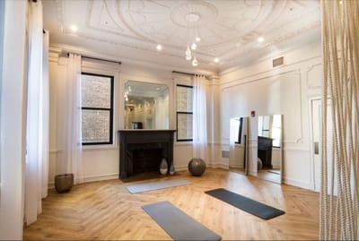 Brightly lit fitness room with yoga mats and a mirror