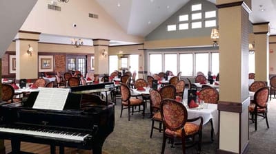 Elegant dining room with piano and tables set for meals
