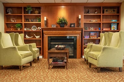 Cozy lounge area with green chairs and a fireplace
