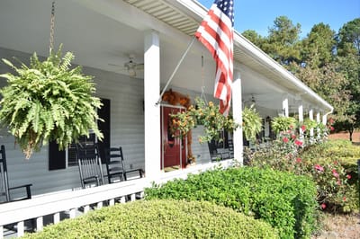 Exterior view of the facility with rocking chairs and garden