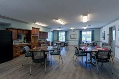 A bright dining room with tables and chairs in an assisted living facility