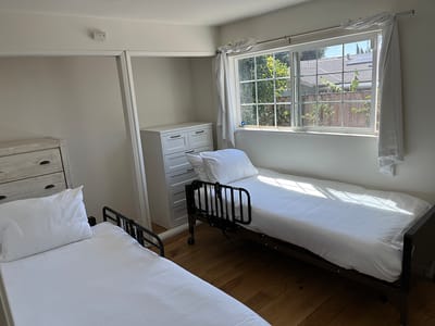 A bright, shared room with two beds and a window