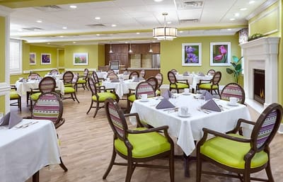 Cozy dining room setup with green chairs and white tablecloths