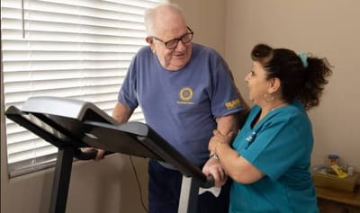Resident exercising on a treadmill with staff assistance