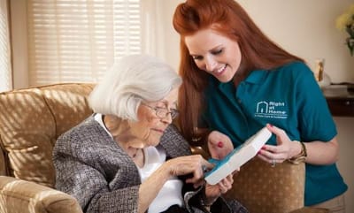 Staff member assisting an elderly resident in a living room