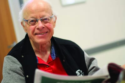 Senior man smiling and reading a newspaper indoors