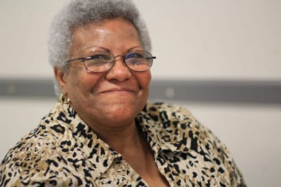 Smiling senior woman with glasses in an indoor setting.