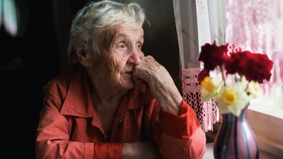 Elderly woman gazing thoughtfully by a window.