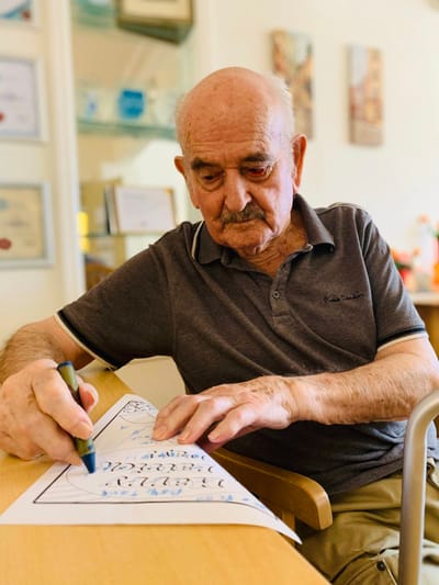 An elderly man coloring in a common area