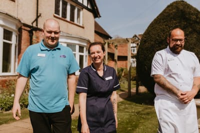 Staff members smiling outside in the garden