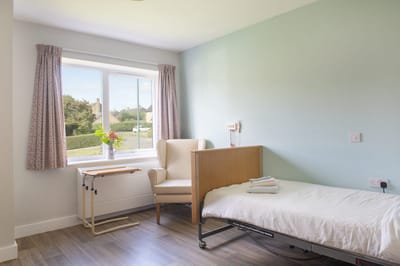 A private room in a senior care facility with a bed and a chair.
