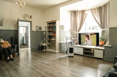 Common area with a resident and a TV displaying a woman outdoors
