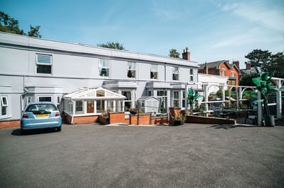 Exterior view of Forest Lodge Care Home with outdoor seating