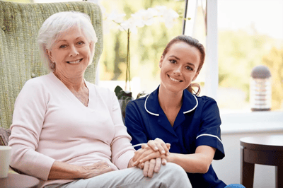 A caregiver and resident smiling together in a common area