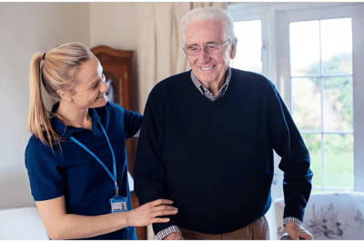 A caregiver assisting an elderly man in a bright room
