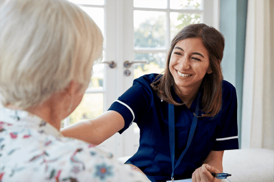 Caretaker smiling while assisting a senior resident
