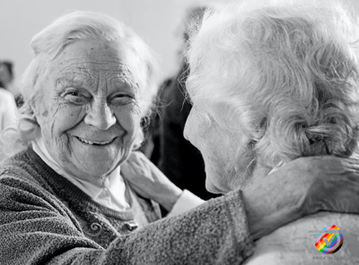 Two smiling elderly women embracing each other