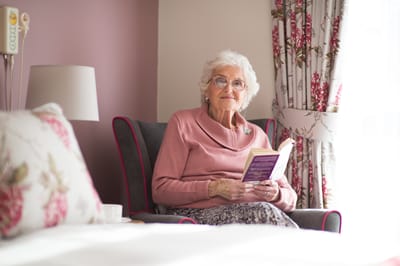 An elderly woman reading in a cozy armchair