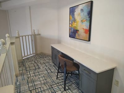 Brightly lit area with desk and artwork on the wall