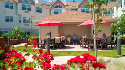 Residents socializing under shaded umbrellas in a garden.