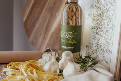 Bottle of wine with pasta and garlic on a wooden surface