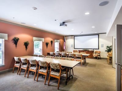 Well-lit common area with seating and a presentation screen