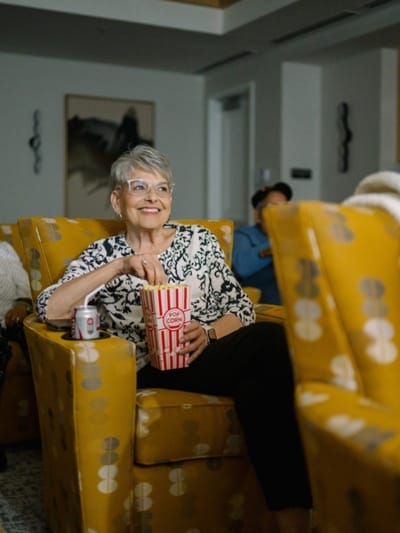 Senior resident enjoying a movie with popcorn in a common area