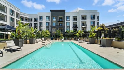 Outdoor pool area with landscaping and building in background