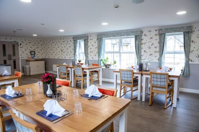 Bright dining area with neatly set tables and floral decor