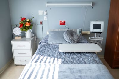 A well-decorated resident room with a bed and floral arrangement