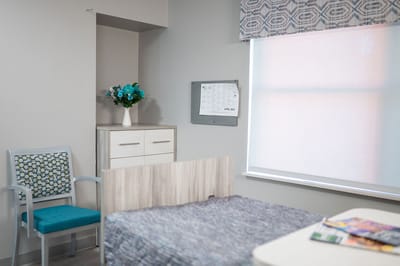 A well-furnished resident room with a bed and a floral arrangement