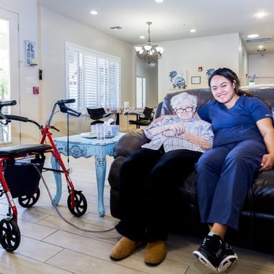 A resident and staff member smiling together in a cozy lounge