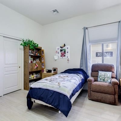 A private resident room with a bed and chair