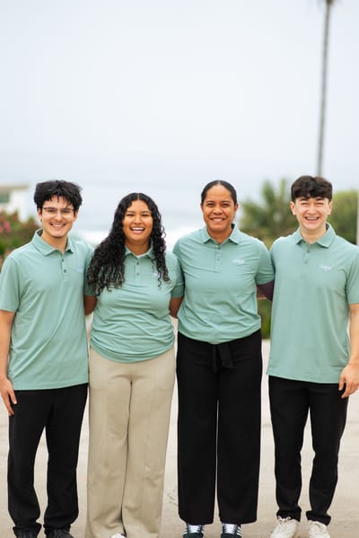Four staff members posing outdoors by a beach