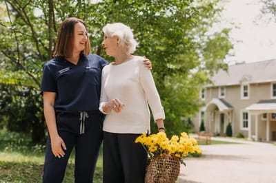 Care staff and resident enjoying time outdoors with flowers