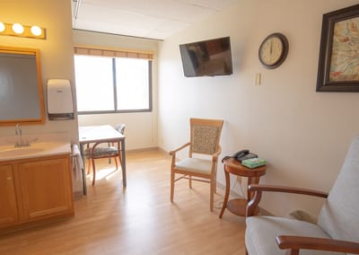 A well-lit private resident room with furnishings